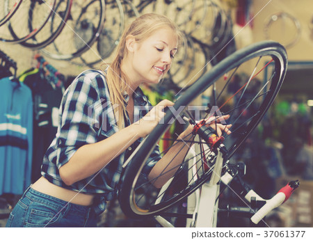 Woman master is fixing wheel of city-bike 37061377