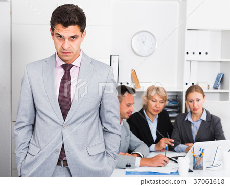 Unhappy man at office with working colleagues Unhappy man at office with working colleagues 37061618