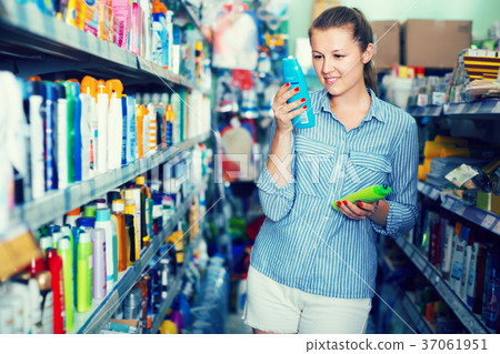 smiling female holding shampoo and conditioner in the hand at the shop 37061951