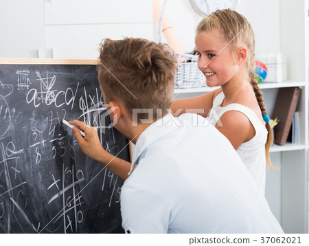 Friends are learning new theme on math and writing task on desk Friends are learning new theme on math and writing task on desk 37062021