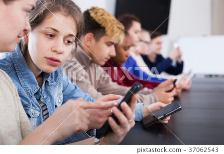 Male and female students playing with smartphones Male and female students playing with smartphones 37062543