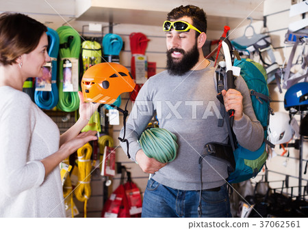 Climbers examining alpinism equipment items in sports shop 37062561