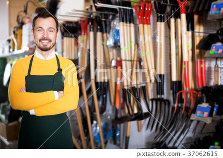 Seller displaying various items in garden equipment shop 37062615