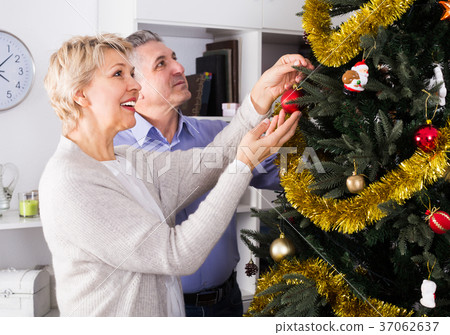 Wife and husband are hang up New Year's toys on a fir-tree Wife and husband are hang up New Year's toys on a fir-tree 37062637