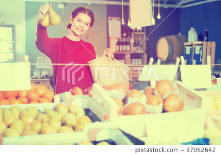 Portrait of brunette girl buying ripe pear in supermarket 37062642