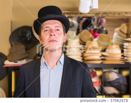 cheerful adult male shopping in botique and try on cylinder hat 37062878