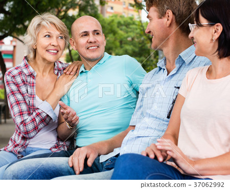 Portrait of mature cheerful males and females talking outdoors 37062992