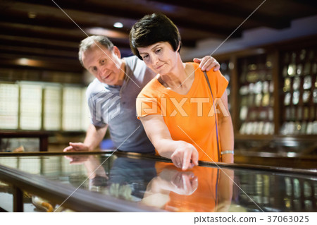 Romantic elderly couple interested in objects of applied arts in museum 37063025