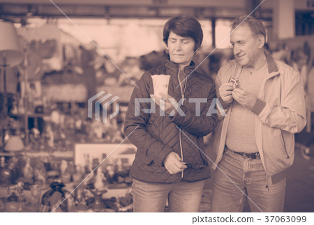 Mature couple looking vintage souvenirs at sale on market Mature couple looking vintage souvenirs at sale on market 37063099