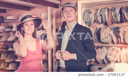 Positive woman and man trying on fashion hats 37063137