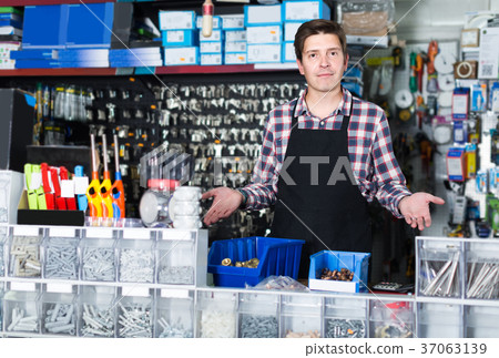 Man standing near the counter and selling details for plumbing in hardware shop 37063139