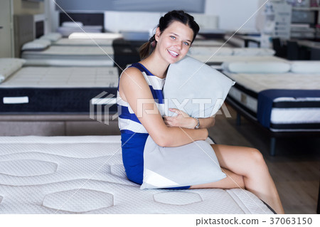Customer female sitting with pillow and testing mattress Customer female sitting with pillow and testing mattress 37063150