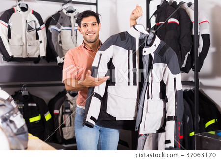 Man is demonstrating new jacket for motorbike in the store. Man is demonstrating new jacket for motorbike in the store. 37063170