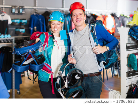 positive girl and guy select gear for hiking and camping in sports shop 37063688