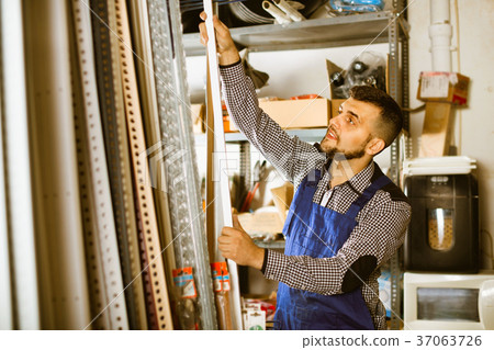 Young man worker examining plastic corners for tiles and floors 37063726