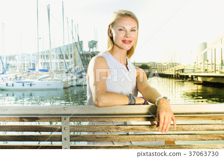 woman sitting near the marina bay at bench woman sitting near the marina bay at bench 37063730