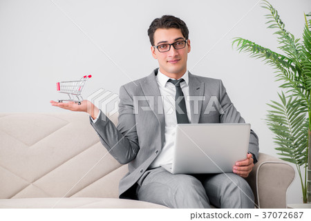 Businessman with laptop and shopping cart Businessman with laptop and shopping cart 37072687