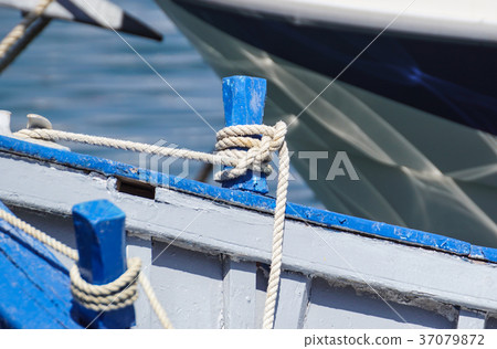 Knotted blue rope laying over the side of a old Knotted blue rope laying over the side of a old 37079872