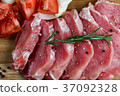 Slices of meat being seasoned for preparation. 37092328
