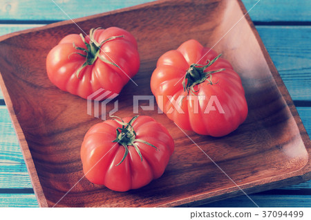 three red ripe tomato with green stalk on a plate three red ripe tomato with green stalk on a plate 37094499