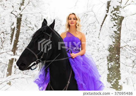 Young woman in long dress riding a horse in winter 37095486