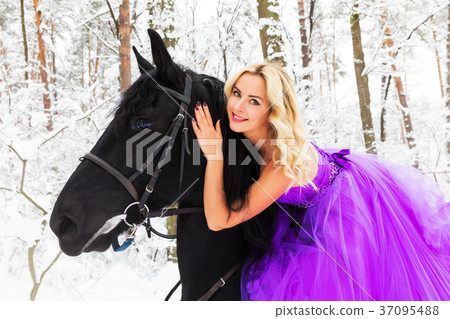 Young woman in long dress riding a horse in winter 37095488