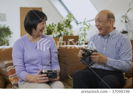 資深夫婦談話與拿著愛好的照相機微笑 資深夫婦談話與拿著愛好的照相機微笑 37098196