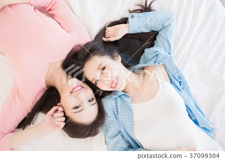 two woman lying on bed 37099304
