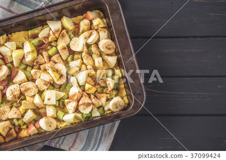 Baking pan with raw dough and cut fruits filling 37099424