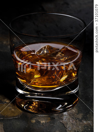 Elegant glass of whiskey with ice cubes on stone Elegant glass of whiskey with ice cubes on stone 37101079