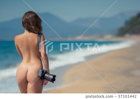 Naked woman in the bikini with camera on the sand 37101442