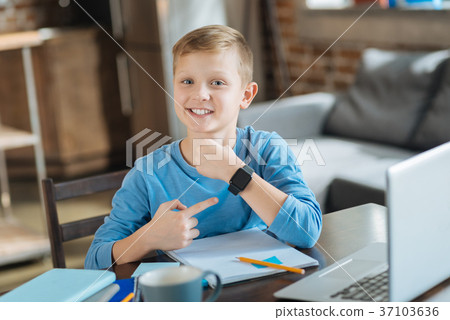 Delighted positive boy pointing at his smartwatch 37103636