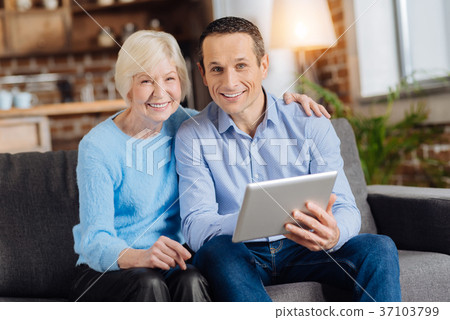 Smiling elderly woman and her son using tablet Smiling elderly woman and her son using tablet 37103799