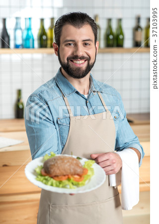 Excited enthusiastic waiter smiling while showing Excited enthusiastic waiter smiling while showing 37103995