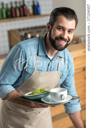 Positive responsible waiter smiling while taking 37104007