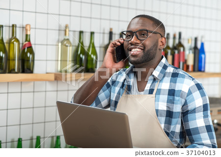 Positive young man talking on the phone while Positive young man talking on the phone while 37104013