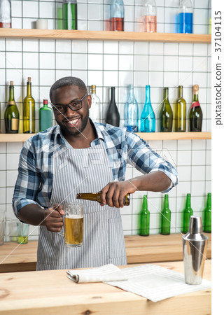 Cheerful skilled barman smiling while pouring beer 37104115