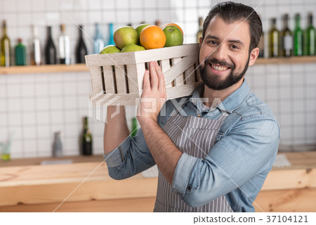 Positive young worker holding a heavy box with 37104121