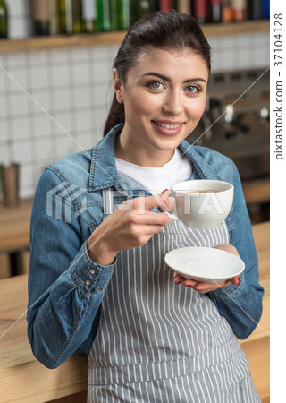 Beautiful smiling waitress drinking tea while 37104128