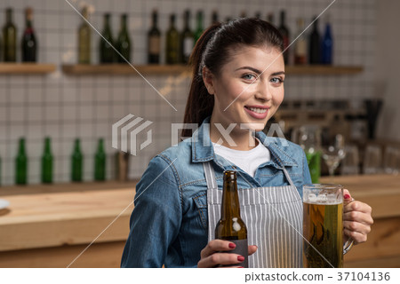Lovely cheerful waitress standing with beer and 37104136