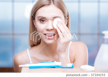 Beautiful woman removing eye makeup with cotton 37104255