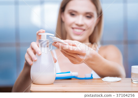 Smiling woman putting skincare product on cotton 37104256