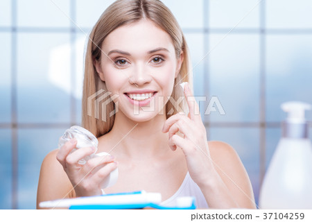 Smiling woman being about to apply cream to her 37104259