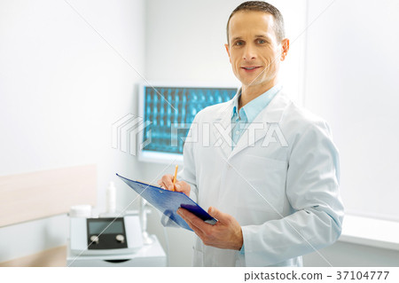 Delighted experienced doctor working in his office 37104777