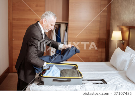 Handsome senior man putting jacket in the suitcase Handsome senior man putting jacket in the suitcase 37107485