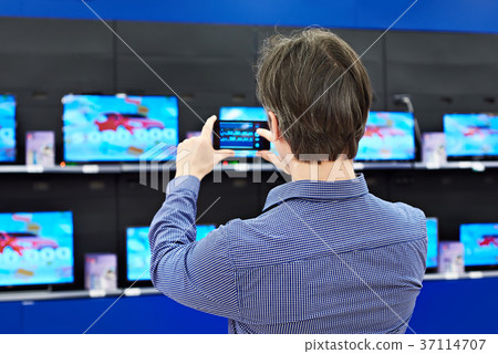 Man shoots with smartphone TVs in shop Man shoots with smartphone TVs in shop 37114707
