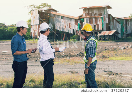 Engineers and investors stand look at old factory Engineers and investors stand look at old factory 37120287