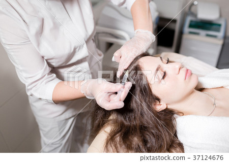 Handsome woman receives an injection in the head 37124676
