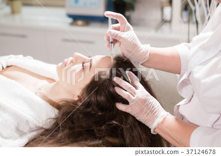 Handsome woman receives an injection in the head 37124678