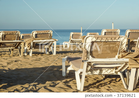 Sun loungers and closed umbrellas at a seaside 37139621